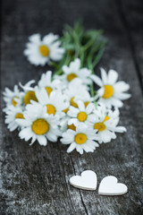 Obraz premium Beautiful fresh daisies decorated with hearts on wooden texture