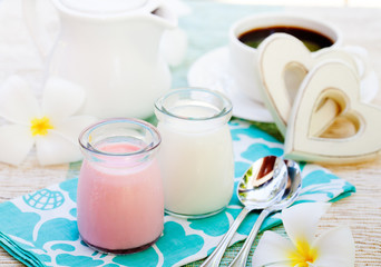 Obraz na płótnie Canvas Homemade yogurt strawberry and vanilla in glass jars Romantic breakfast background with wooden heart, frangipani and orchid flower