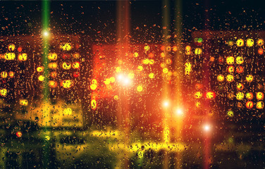 Drops of water on window glass after rain, with blurred lights o