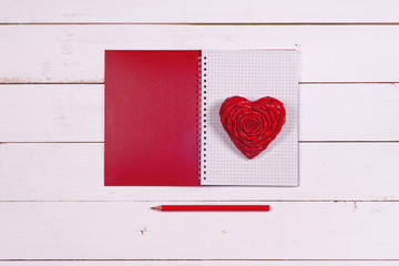 Notebook and heart on a white rustic background. Valentine's Day. Top view. Space for text.