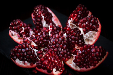 Fresh pomegranate and seeds on black