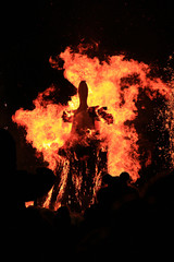 Traditional burning of Maslenitsa Scarecrow on seeing Russian winter on last day of Shrovetide in dark evening. Burning effigy on black background. Vertical orientation