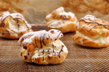 Cream puff cake with filling and chocolate icing. Catering set.