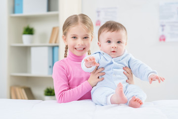 Little positive girl holding infant