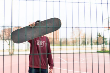 Guy holding his Skate on a Court