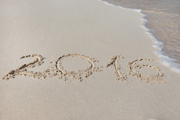 Inscription 2016 on sandy beach with wave's foam