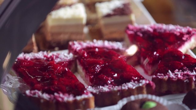 Show window in a grocery shop or a bakery. Tasty and delicious  potato cakes, tarts with strawbery, cream,  jelly finishing, red currants and icing shugar.