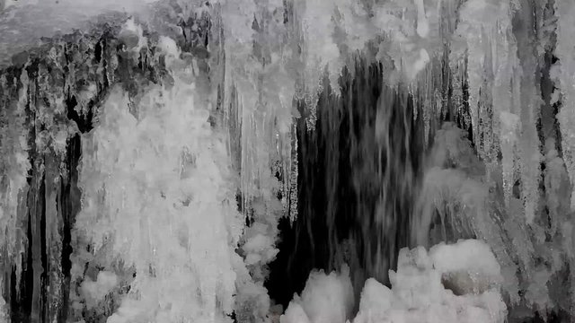 A small waterfall streaming behind frozen iceicles, shot with a canon 6D