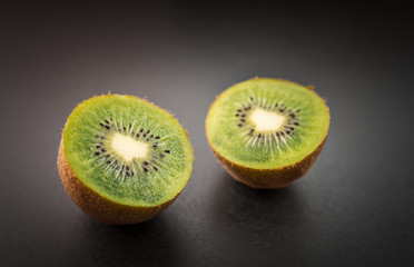 Ripe kiwi fruit, half full on dark background. Selective focus with shallow depth of field.