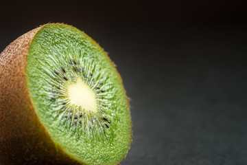 Ripe kiwi fruit, half full on dark background. Selective focus with shallow depth of field.