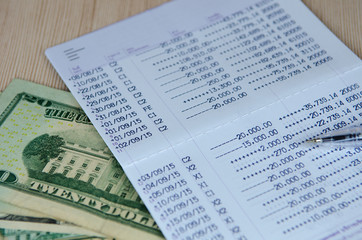 Pen on bank account passbook with dollar banknote, selective foc