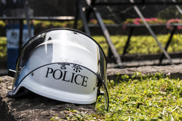 Police helmet sitting on the ground in front of police barricades. Partially visible are the...