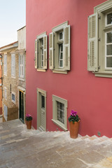 Traditional alley at Nafplio in Greece with pink walls and flowers.
