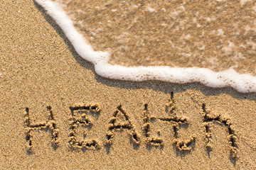 Health - inscription on sand beach with the soft wave.