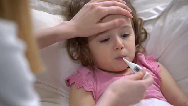 Woman is measure the temperature of little girl. Close-up. Home quarantine coronavirus, self isolation.