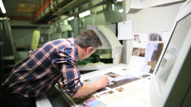Man in printing house controling sample before edition