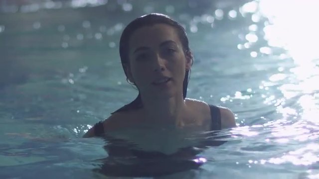 Young attractive female stands in water in a pool in a spa wellness center. Shot on RED Cinema Camera.