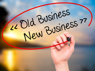 Man Hand writing Old Business - New Business with black marker o