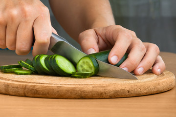 hands slicing cucumber  for salad, closeup
