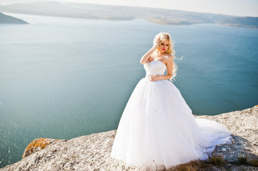 Fototapeta na wymiar Charming blonde bride on landscapes of mountains, water and blue
