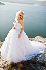 Charming blonde bride on landscapes of mountains, water and blue