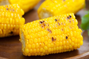 Grilled corn on the cob with salt and butter on a wooden plate