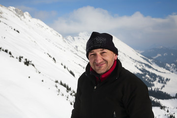 Fototapeta na wymiar Happy hiker; man in 40-50s enjoying hiking in winter mountains. 