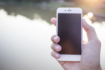 Man hand holding smartphone against on smooth background.
