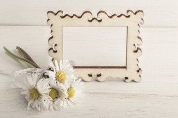 daisy flowers and an empty frame on wooden background