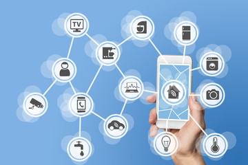 Fototapeta premium Home automation concept with hand holding modern smart phone to control home devices like a smart thermostat and sensor via the world wide web