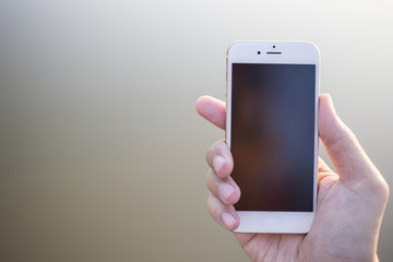 Man hand holding smartphone against on smooth background.