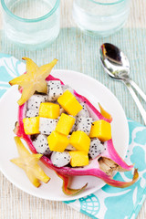 Tropical fruit salad in pitahaya, mango, dragon fruit bowls with a glass of juice Diet, healthy fruit salad Healthy breakfast, weight loss concept