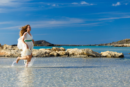 19 okt 2013,  Elafonisi beach, Crete, Greece. Buatiful woman in a white dress runs on the water