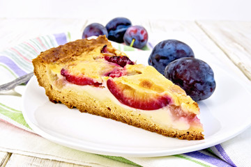 Pie plum with sour cream in plate on light board