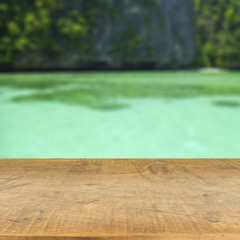 Wood table top on blurred blue sea background used for display y