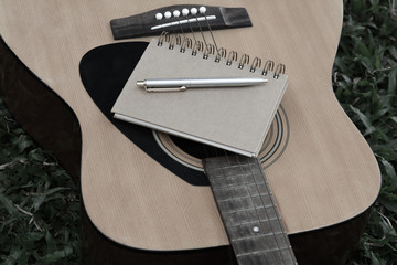 Concept song composer.Notebook and pen on the guitar