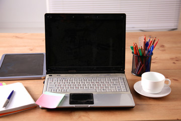 Office table with blank notepad and laptop 
