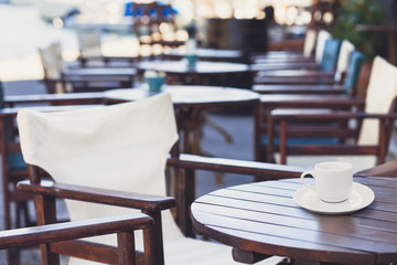 A cup of coffee on table with cafe at the background
