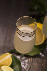 Refreshing lemon and lime cocktail and fresh citrus over the old wooden background, selective focus