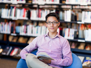 Obraz premium Happy male student holding books at the library
