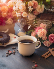 Morning coffee in a white cup on a brown table with flowers and cinnamon