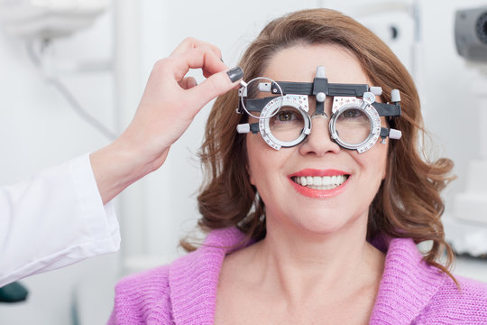 Cheerful female optician is examining human eyes