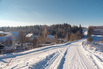 Fototapeta premium Photo of the winter country road and village. Trees covered with snow. Winter landscape. Russia.