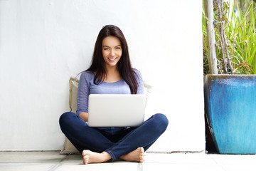 Happy young woman sitting on floor with a laptop - Powered by Adobe