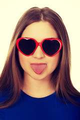 Teen woman in sunglasses shows tongue.