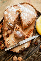 
pastries, cake with walnuts and a banana with powdered sugar on a wooden background