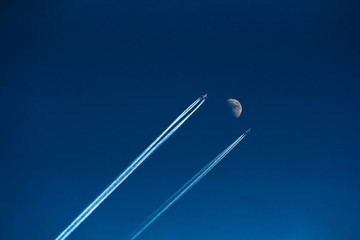 two aircraft flying in the sky next to the moon