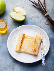 Apple tart, puff pastry strips with vanilla custard on a stone background