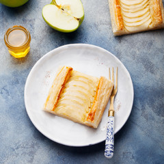 Apple tart, puff pastry strips with vanilla custard on a stone background