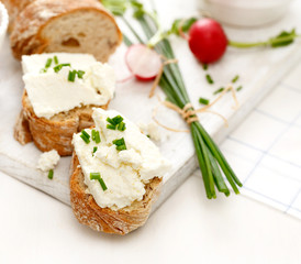 Fototapeta na wymiar Canapes with curd cheese and fresh chive on a white table